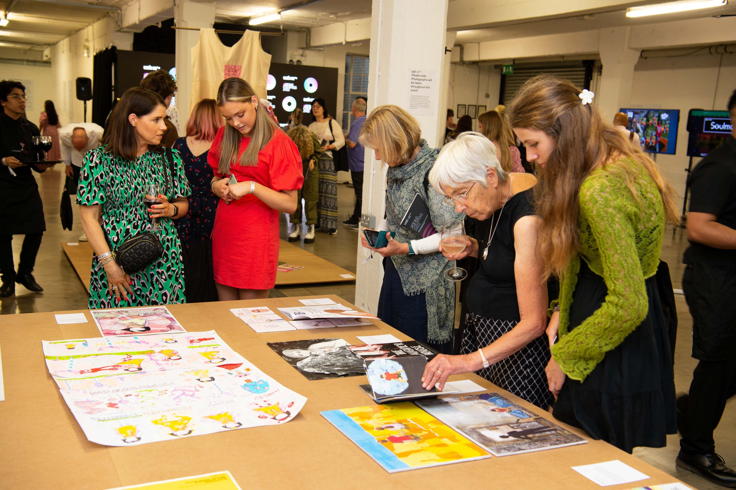 Picture of a group of people looking 2d graphic artworks on a table